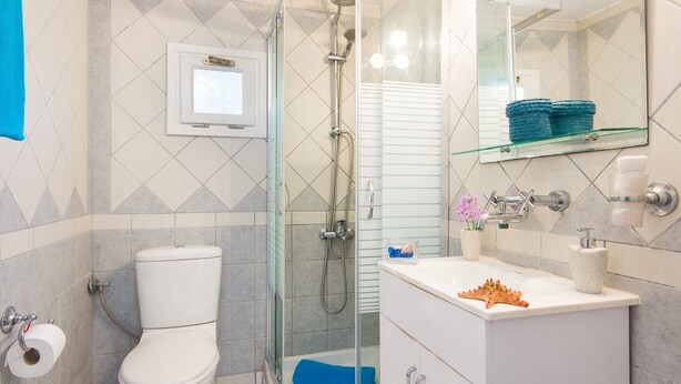 Et badeværelse med toilet, bruser og vask.
