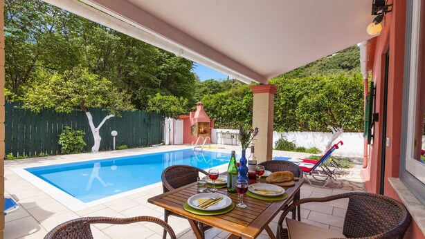 Un espace aménagé au bord de la piscine, avec une table dressée pour les repas, entourée de chaises en osier.