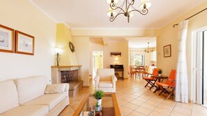 A living room with a sofa, a coffee table, a fireplace, and a dining area with chairs.