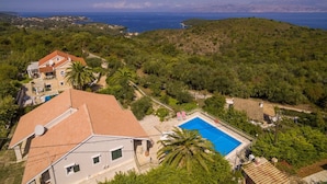 A residential area with houses, a swimming pool, and a view of the sea.