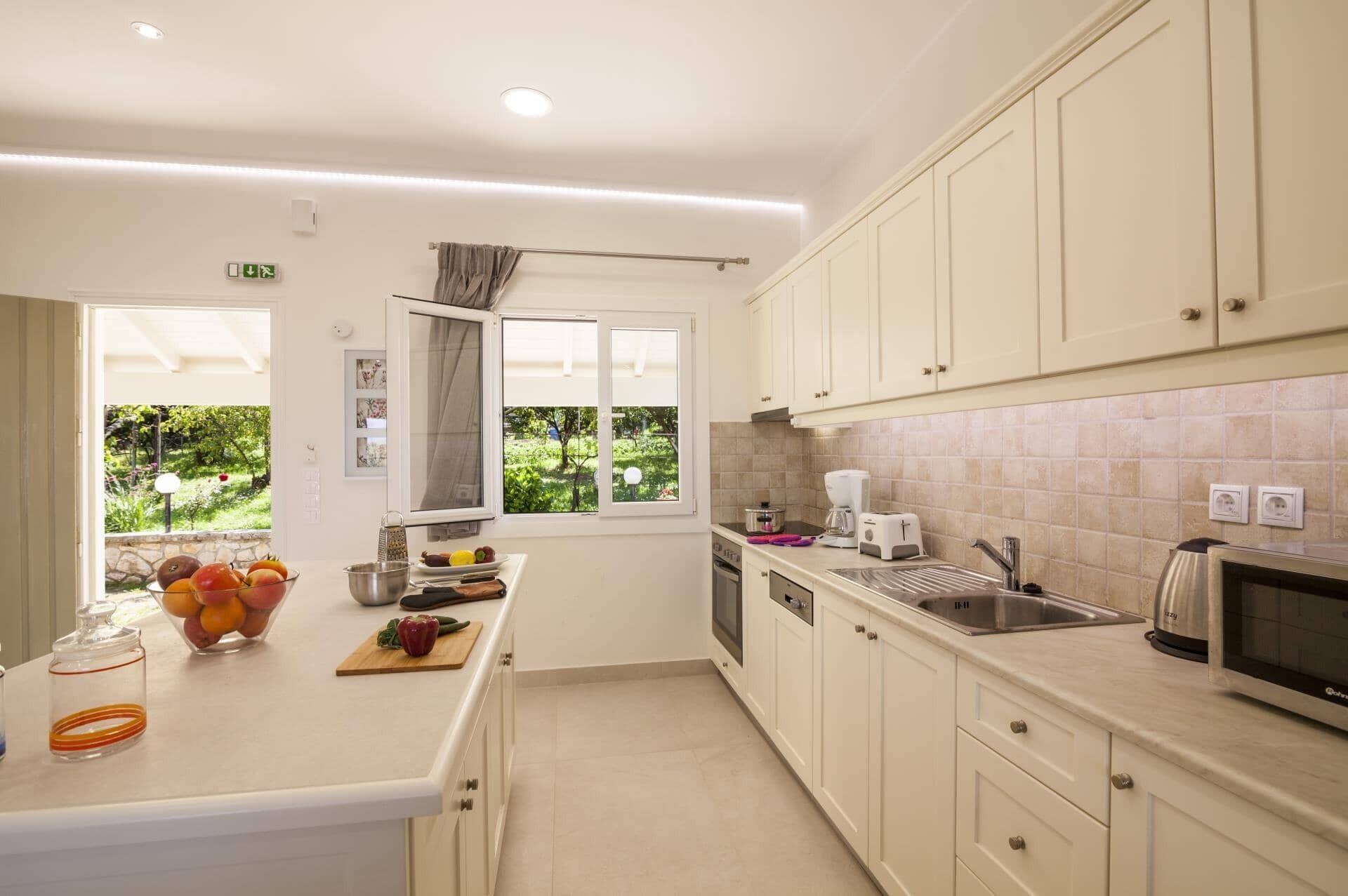 A modern kitchen with a large island, built-in appliances, and a view of greenery outside.