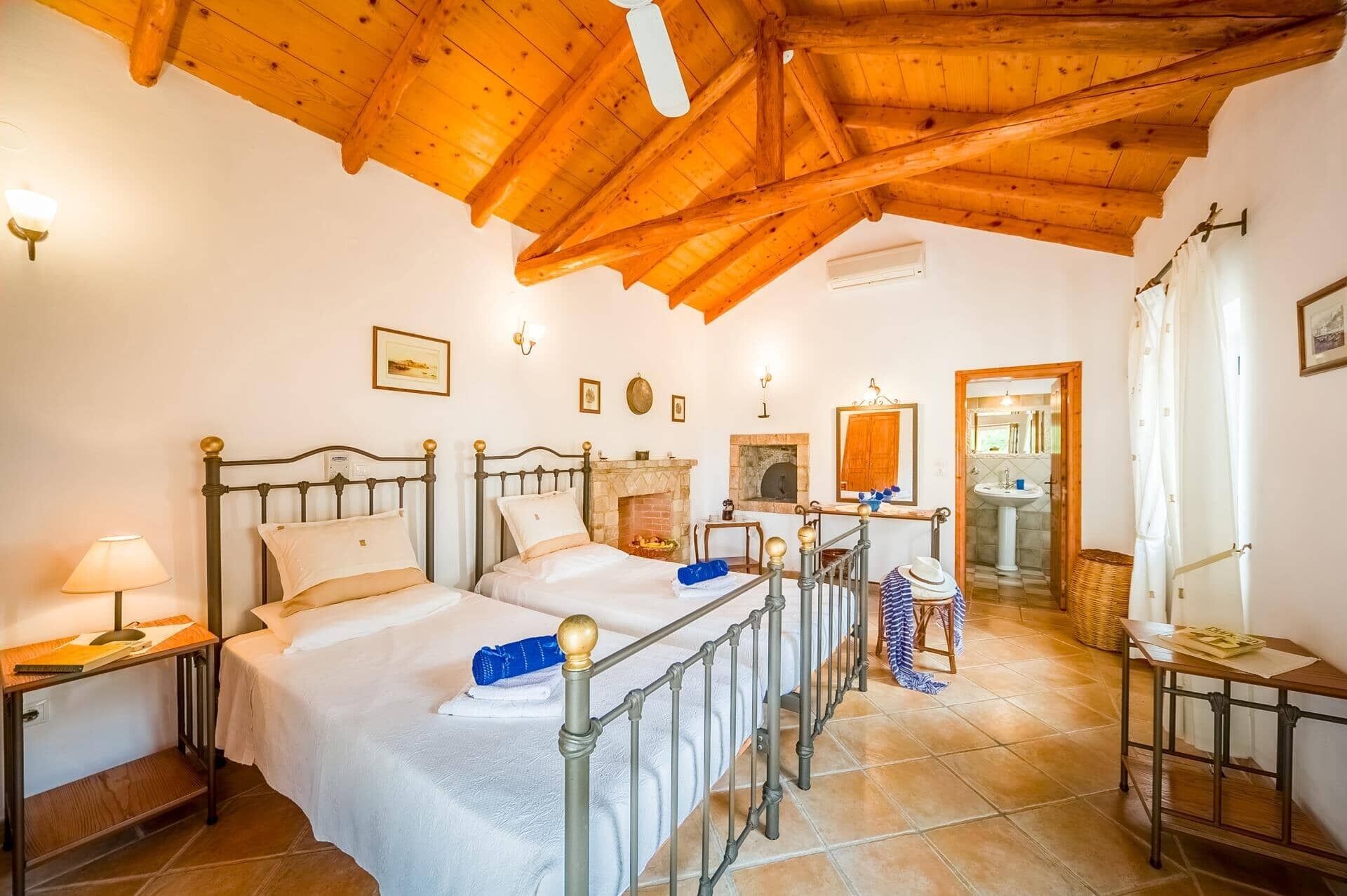 Una habitación con dos camas, chimenea, espejo, baño y techo de madera.