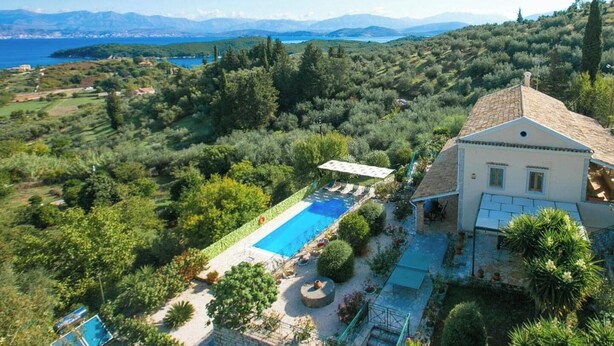 Uma villa com piscina, rodeada por vegetação exuberante e montanhas ao fundo.
