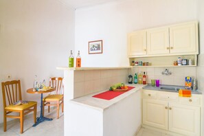 A compact kitchen with a dining area, featuring a small table, chairs, and a red placemat.