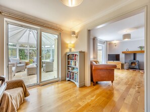 A spacious living area with a large sliding glass door leading to a patio, a fireplace, a bookshelf, and a television.