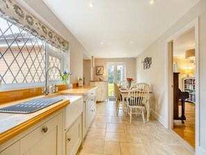 Una cocina con ventana, lavamanos y comedor con sillas y mesa.
