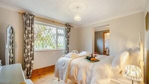 Ein Schlafzimmer mit Bett, Nachttisch, Lampe und einem Fenster mit Vorhängen.
