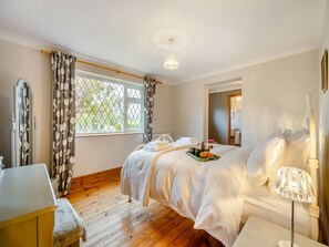A bedroom with a bed, bedside table, lamp, and a window with curtains.