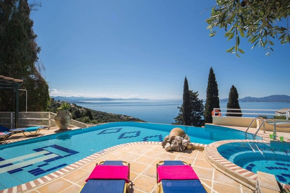 A pool with a clear view of the sea and mountains in the background.