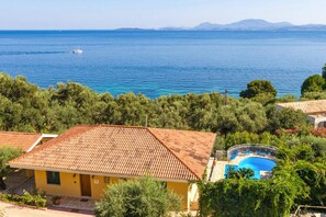 A coastal property with a swimming pool, a yellow building, and a view of the sea.