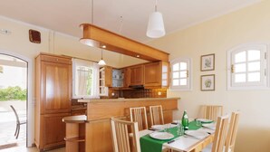 Una cucina moderna con mobili in legno, un'isola centrale e un'area pranzo con tovaglia verde.