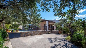 Una casa con un muro in pietra, una piscina e un portico coperto.