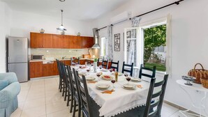 Cozinha moderna com armários de madeira, uma mesa de jantar posta para seis pessoas e vista para o exterior.