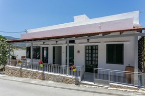 Un bâtiment à deux étages, doté d’une façade blanche, de volets noirs et d’un toit recouvert de tuiles rouges.