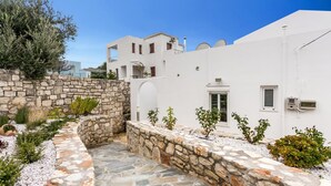 A white building with a stone wall and a stone pathway. - Villa Almyrida View by Villa Plus (Apokoronos)