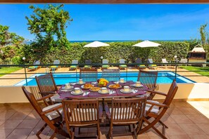 A dining table with chairs and a pool view.