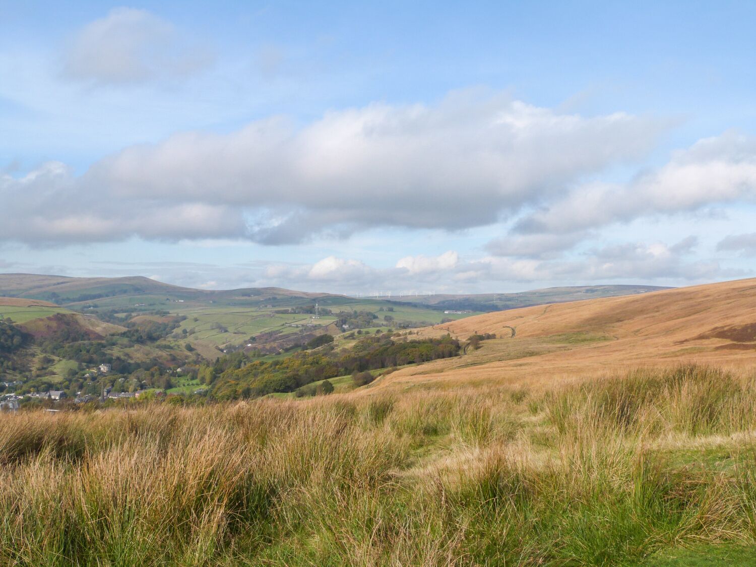 A panoramic view of a hilly landscape with a small village in the valley.