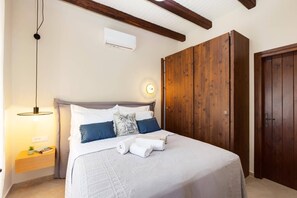 Un dormitorio con cama, mesita de noche, lámpara colgante, armario y aire acondicionado.