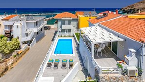 A rooftop pool with sun loungers, a clear view of the sea, and a mix of modern and traditional architecture. - Villa Areva by Villa Plus (Panormos)