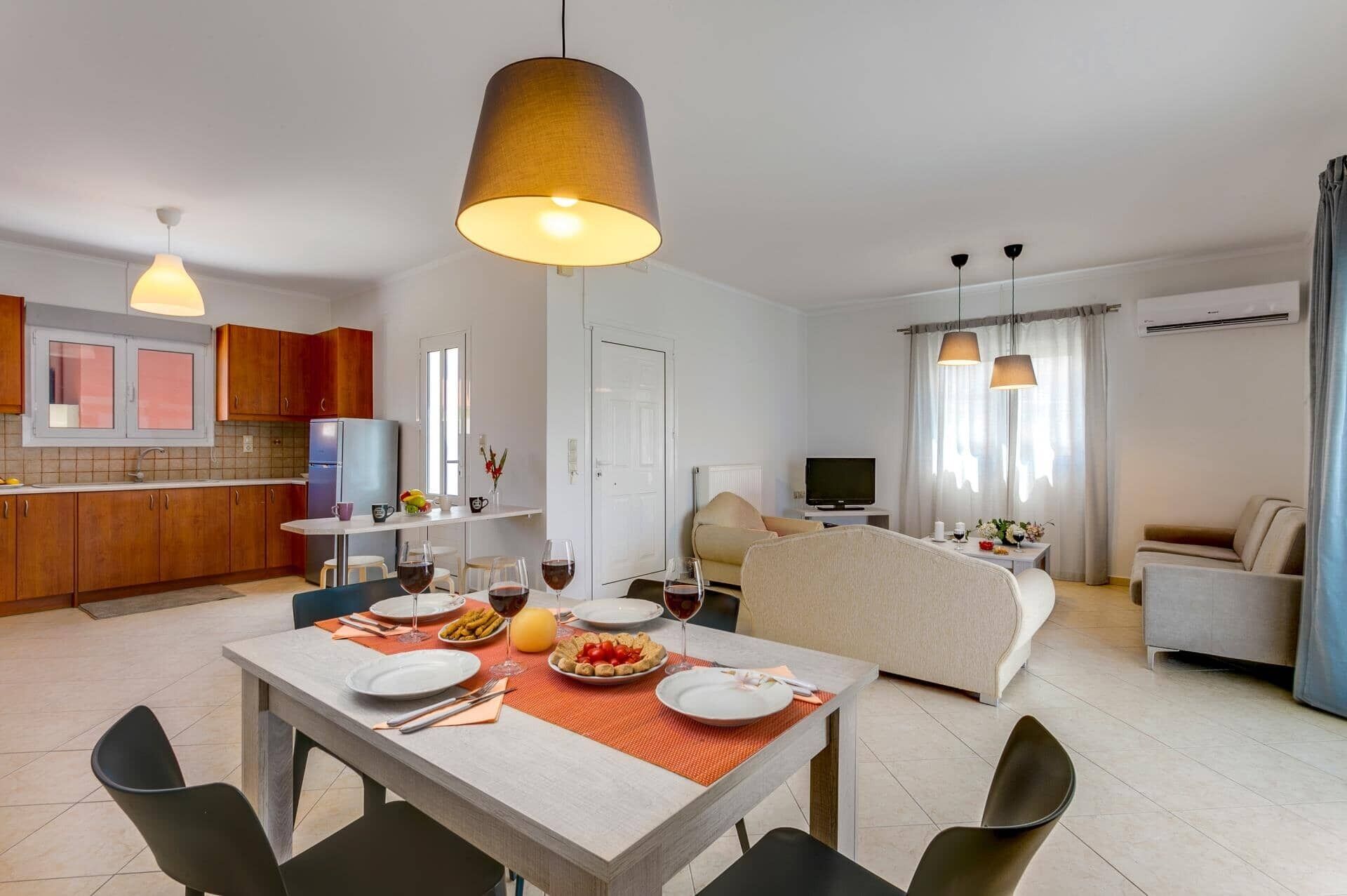 A modern apartment with a dining area, kitchen, living room, and a TV.