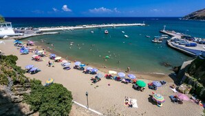 A beach with clear waters, umbrellas, and boats. - Villa Areva by Villa Plus (Panormos)