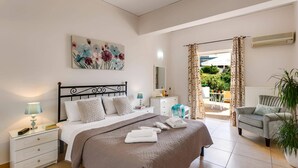 A bedroom with a bed, bedside tables, a mirror, a painting, and a view of the outdoors. - Villa Capri Crete by Villa Plus (Chersonisos)