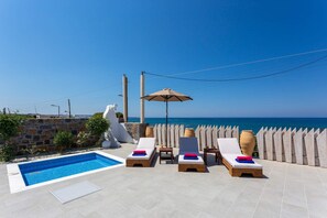 Ein Poolbereich mit Liegestühlen, einem kleinen Tisch und einem Sonnenschirm.