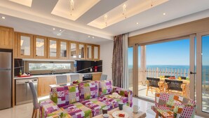 Een moderne keuken met houten kastjes, een eetgedeelte met kleurrijke, bewerkte bekleding, en een balkon met uitzicht op zee.