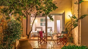 Un espace extérieur accueillant, aménagé avec une table et des chaises, entouré de verdure et agrémenté d’un grand vase.
