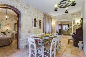 Un comedor con pared de piedra, una araña y una escalera que sube a otro nivel.