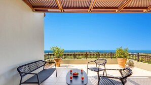 A balcony with two black metal chairs, a small round table, and two potted plants.
