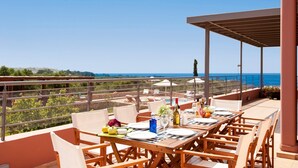 An outdoor dining area with a view of the sea, a pool, and a covered section. - Villa Horizon by Villa Plus (Kampani)