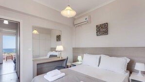 A hotel room with a bed, bedside tables, a desk, a chair, a mirror, an air conditioning unit, and a view of the outside. - Villa Horizon by Villa Plus (Kampani)