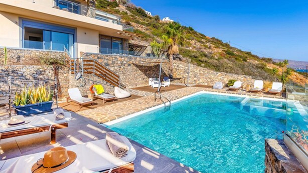 A modern villa with a pool, stone walls, and a hillside view. - Villa Elounda Pelagos by Villa Plus (Agios Nikolaos Municipality)