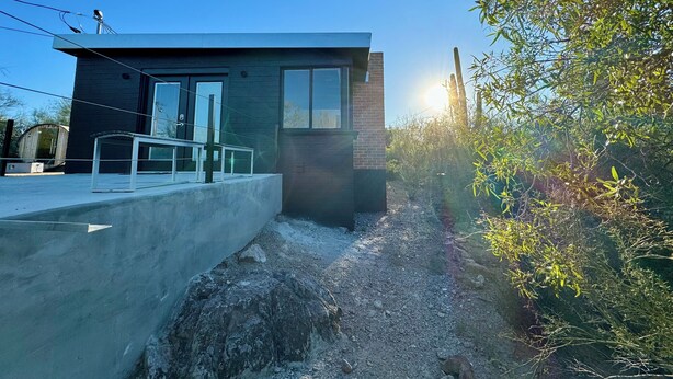 A modern two-story house with a concrete staircase leading to a glass door.