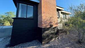 A modern building with a black facade and a brick chimney.