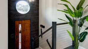 Eine moderne Treppe mit einer Holztür, einem Rundfenster und einem Blumentopf.