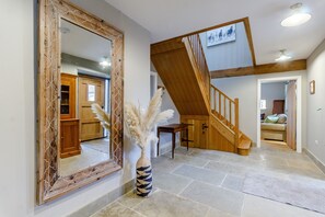 A spacious hallway with a large mirror, a wooden staircase, and a vase with pampas grass. - The Hay Barn (Doncaster)