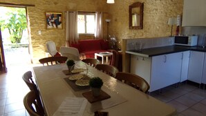 Ein Essbereich mit einem Tisch für vier Personen, Stühlen, einer Küche mit Mikrowelle und einer Steinwand.