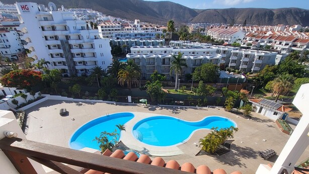 Vista de um hotel com área de piscina, incluindo duas piscinas e um terraço com guarda-corpo.