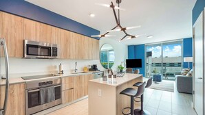 A modern kitchen with a central island, stainless steel appliances, and a contemporary light fixture. - One Bedroom Condo King Bed With City Views (Miami)