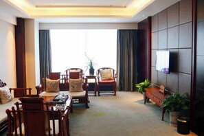 Een moderne hotelkamer met een groot raam, een flatscreen televisie aan de muur, houten meubels en een klein tafeltje met dienblad.
