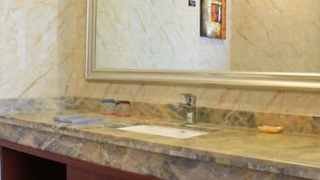 Un baño con encimera de mármol, un lavabo y un espejo.