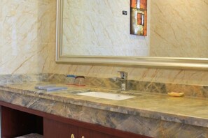 Une salle de bain avec un comptoir en marbre, un lavabo et un miroir.