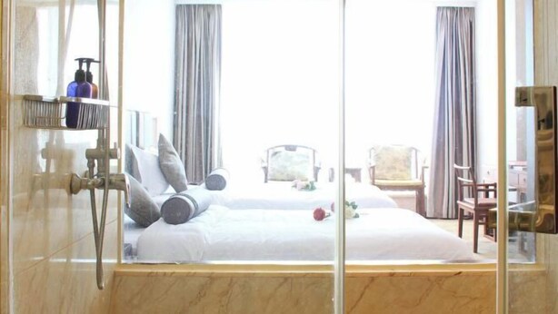 A hotel room with a large bed, a shower area, and a view of the outside. - Lisan Garden Hotel (Ruichang)