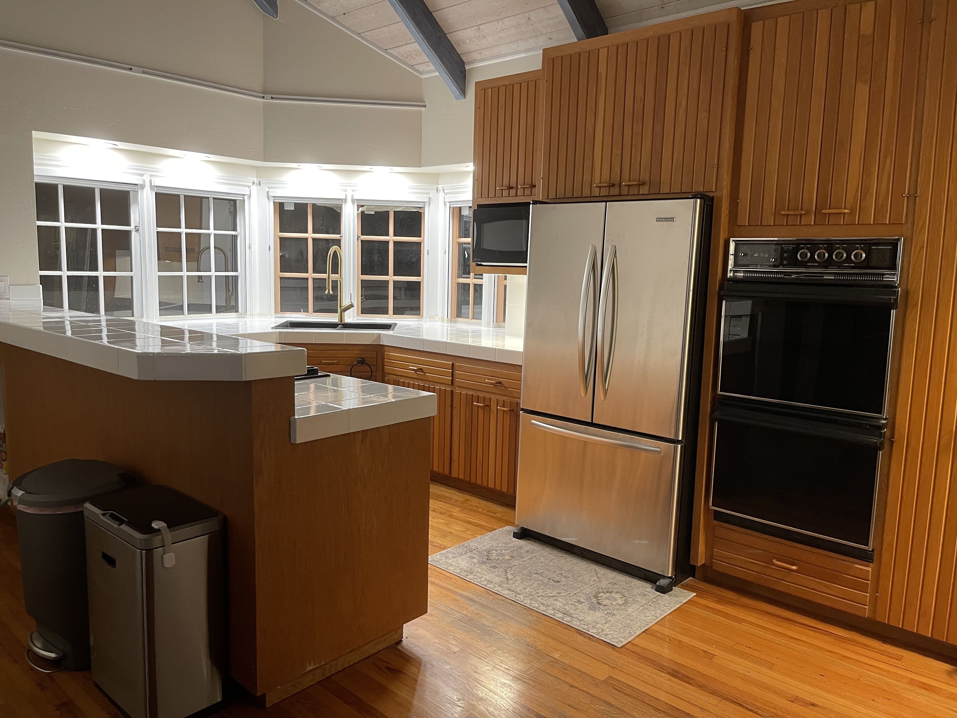 Une cuisine moderne avec des meubles en bois, des appareils électroménagers en acier inoxydable et une grande fenêtre.