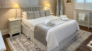 Une chambre bien rangée, avec un lit, des tables de chevet, un miroir et un radiateur.