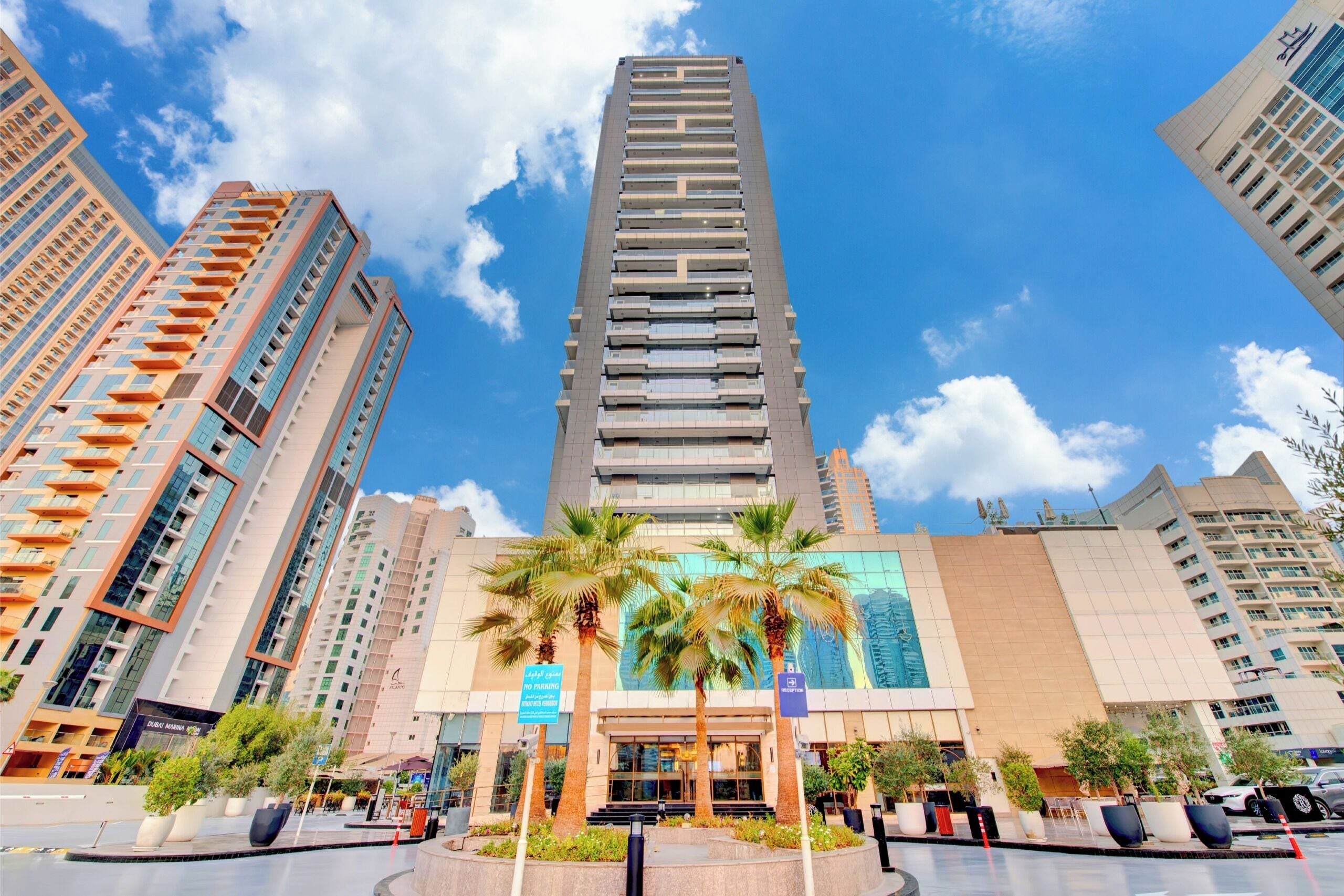 A high-rise hotel with a modern design, featuring a central reception area and multiple balconies.
