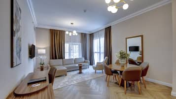 A modern living room with a sofa, dining table, chairs, and a TV.