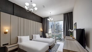 Ein Hotelzimmer mit zwei Betten, einem Schreibtisch, einem Fernseher und Blick auf die Stadt.